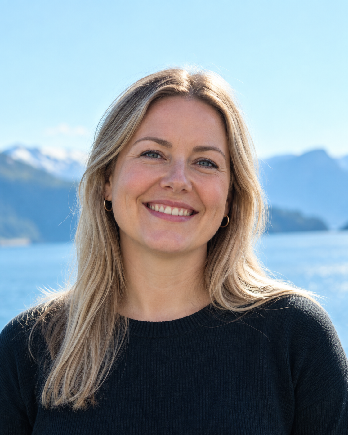 Smilande kvinne ved fjorden. Mellombels bilete.